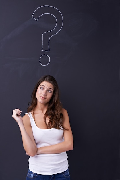 J'ai tellement de questions Jeune femme réfléchie debout sous un dessin à la craie d'un point d'interrogation