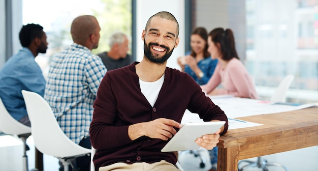 J'ai tout ce dont j'ai besoin ici Portrait d'un beau jeune homme utilisant sa tablette assis dans la salle de réunion lors d'une réunion