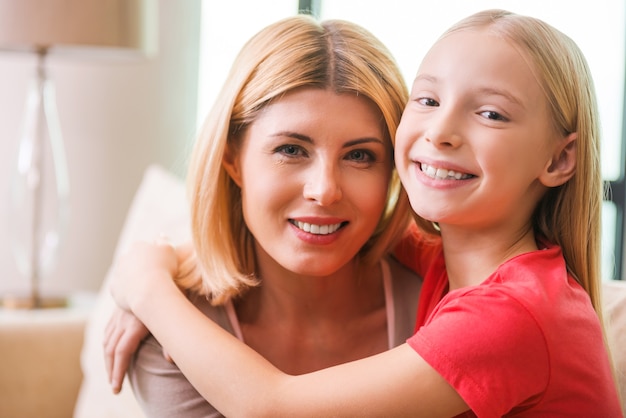 J'aime ma mère! Heureuse mère et fille se liant l'une à l'autre et souriant alors qu'elles étaient assises ensemble à la maison