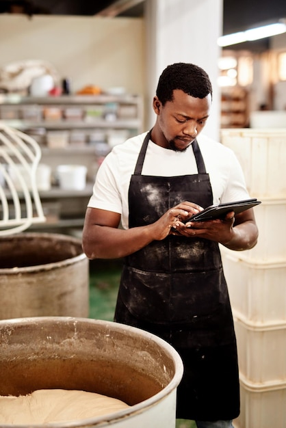 J'enregistre les temps pour chaque tâche Photo recadrée d'un homme utilisant une tablette numérique tout en travaillant dans une boulangerie