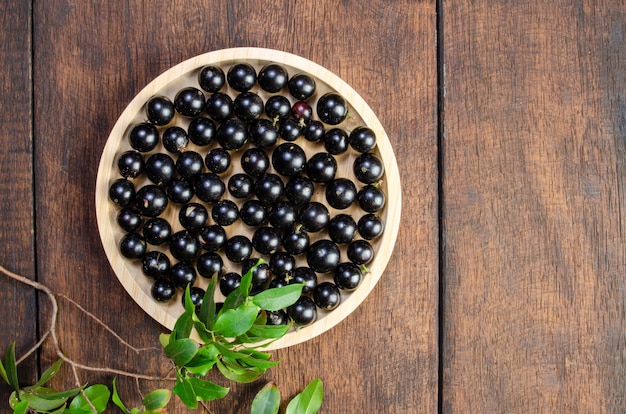 Jabuticaba, Jabuticabas fraîchement récolté dans des pots et des paniers disposés sur du bois rustique, vue de dessus.