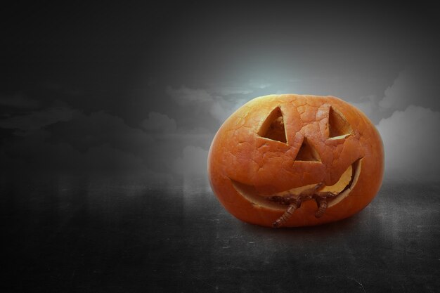 Jack-o-Lantern avec des vers sur une table en bois avec le fond de scène de nuit