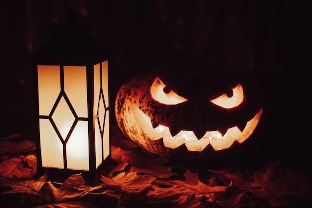 Jackolantern à tête de citrouille d'Halloween et lanterne illuminée sur fond noir