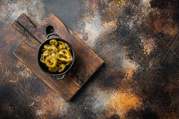 Jalapenos marinés verts et biologiques dans un bol, sur fond rustique sombre, vue de dessus à plat avec espace de copie pour le texte