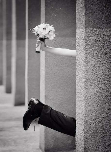 Jambe du marié et main de la mariée avec un bouquet