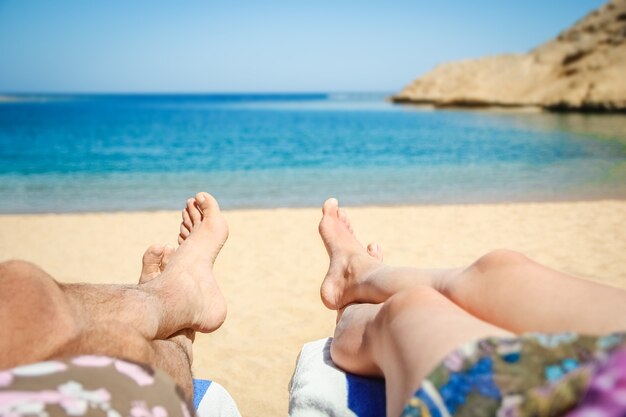 Une jambe d'homme et de femme au bord de la mer sur une surface de voyage de vacances.