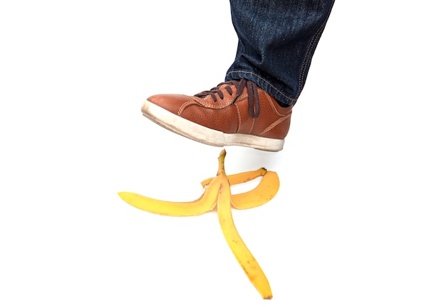 Jambe de l'homme marchant sur la peau de banane, photo conceptuelle