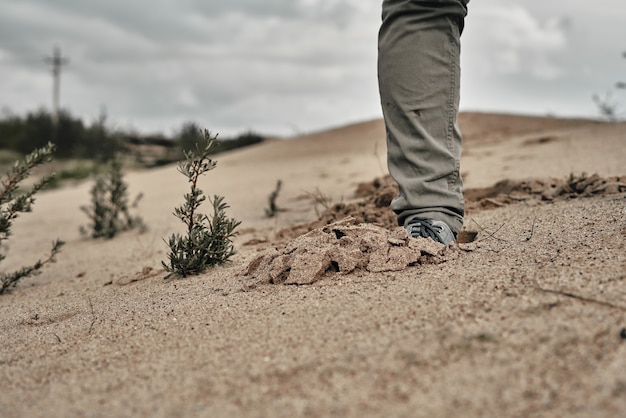 La jambe d'un homme se dresse sur le sable humide