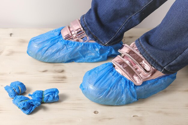 Jambes D'adolescent Avec Des Baskets Roses Et Des Couvre-chaussures Jetables  Bleus Sur Un Plancher En Bois Hygiène Et Protection Dans Les Bureaux Des  Services Médicaux Et Hospitaliers