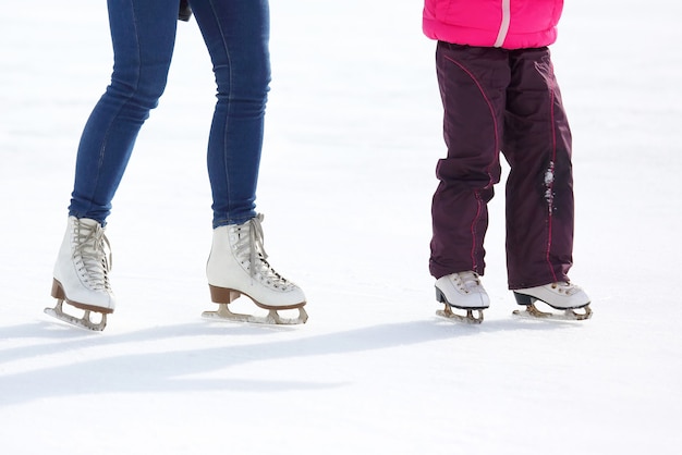 Les jambes d'un adulte et d'un enfant patinant sur la patinoire