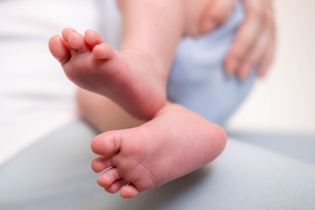 Photo jambes de bébé bouchent mère aimante nourrissant son petit garçon enfant tenant sur les mains étreignant bébé