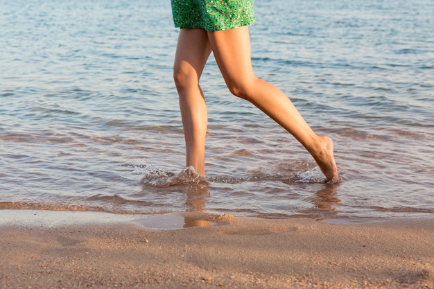 Jambes de belle fille en cours d&#39;exécution sur la plage. jolie fille marchant sur l&#39;eau