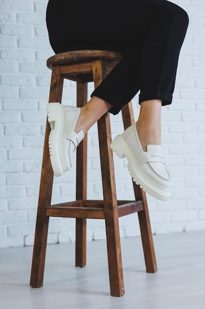 Jambes d'une belle jeune femme en pantalon noir et mocassins en cuir blanc élégants et modernes Nouvelle collection de chaussures pour femmes printemps été 2022