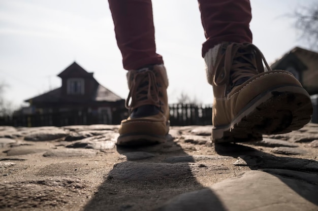 Les jambes en bottes se promènent le long du vieux pavé pavé de pierre, en arrière-plan des maisons en bois.