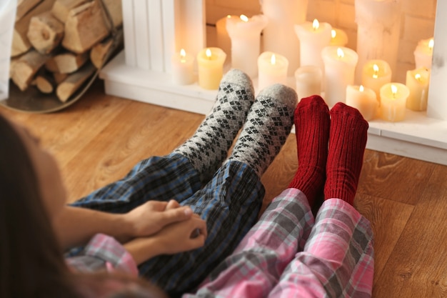 Photo jambes de couple se reposant devant la cheminée à la maison en vacances de noël