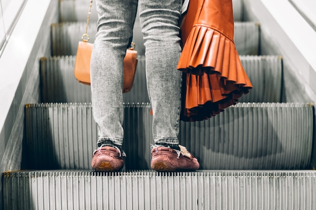 Jambes debout sur l'escalator d'un centre commercial