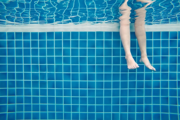 Des jambes drôles de famille sous-marine en piscine, vacances et concept de sport