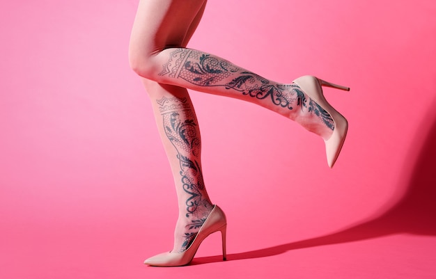 Jambes élancées sexy d'une jeune femme en collant rose avec motif floral décoratif