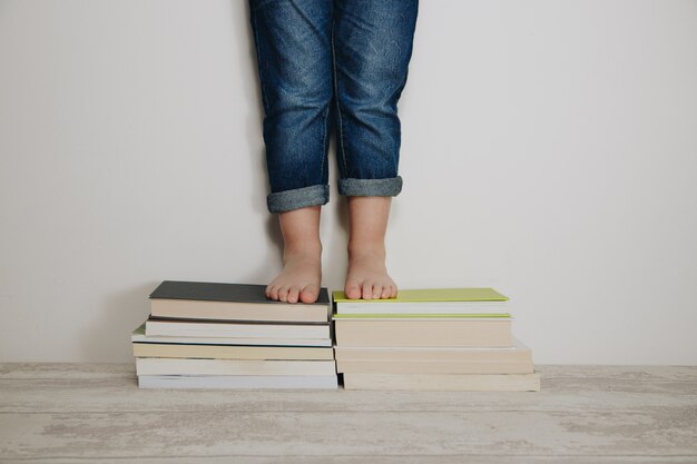 Jambes d'un enfant sur une pile de livres