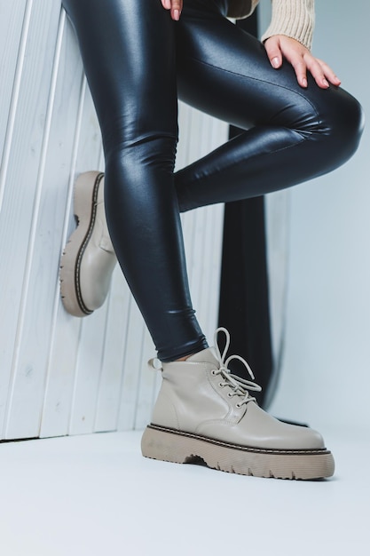 Jambes féminines en bottes d'automne en cuir beige Une fille se tient dans un magasin et mesure des chaussures