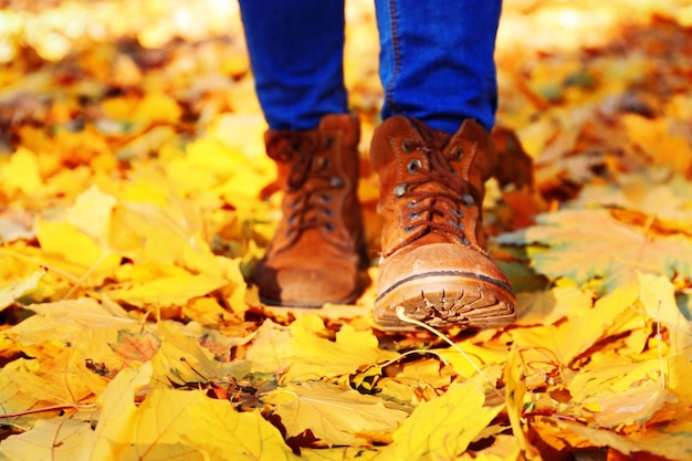 Jambes féminines en bottes sur les feuilles d'automne