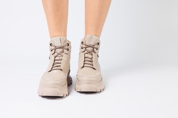 Jambes féminines en chaussures en cuir beige de la nouvelle collection sur fond blanc Jambes féminines en chaussures à la mode en écocuir printemps 2022