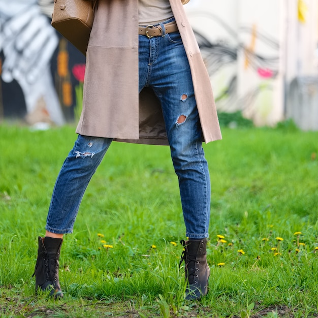 Jambes féminines en jeans copain posant sur l&#39;herbe verte