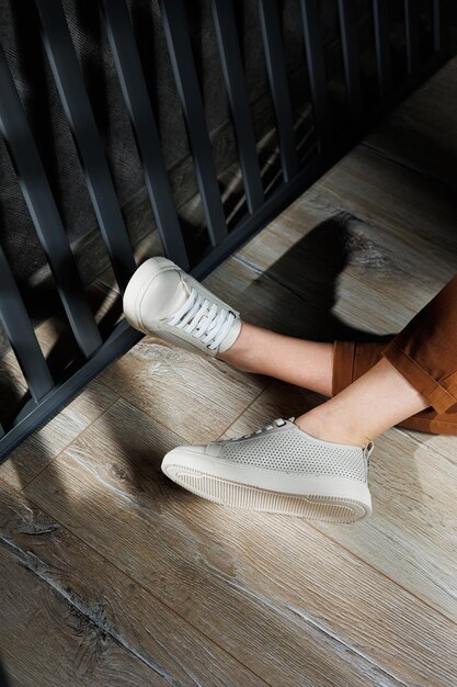 Photo jambes féminines minces dans un pantalon gros plan dans des baskets de sport décontractées beige chaussures en cuir féminines