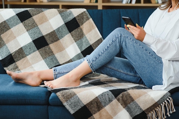 Jambes féminines minces en jeans sur le canapé