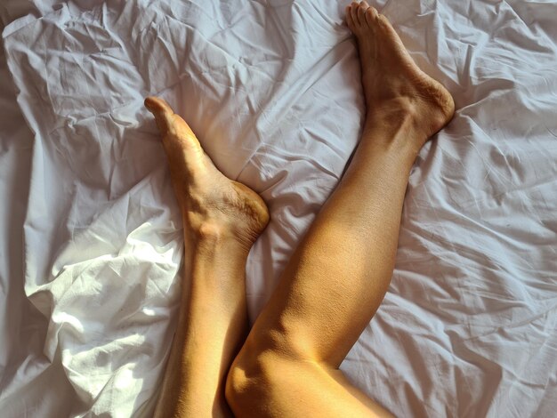 Jambes féminines parfaites et belles minces sur le lit