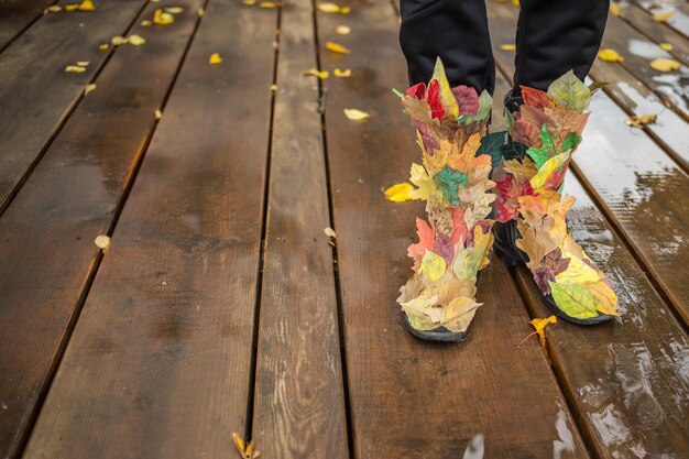 jambes féminines portant des bottes avec concept de feuilles mortes décorées