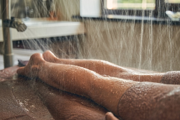 Jambes féminines prenant une douche à l'hôtel de luxe spa resort