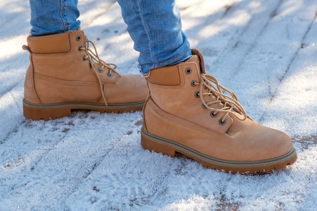 Les jambes de la femme aux bottes brunes debout sur la neige