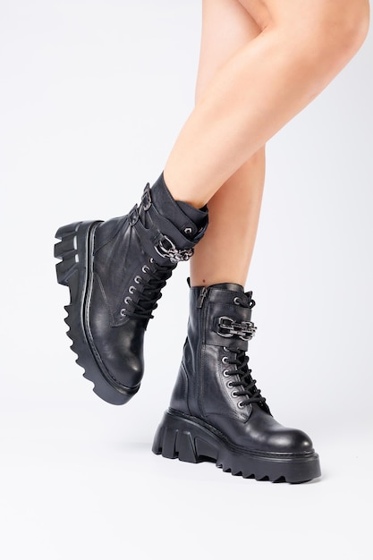 Jambes d'une femme en bottes en cuir noir d'une nouvelle collection sur fond blanc jambes d'une fille en bottes en cuir à la mode printemps 2022