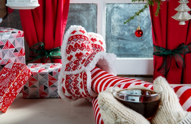 Jambes de femme avec des chaussettes et des pantoufles, boire du thé