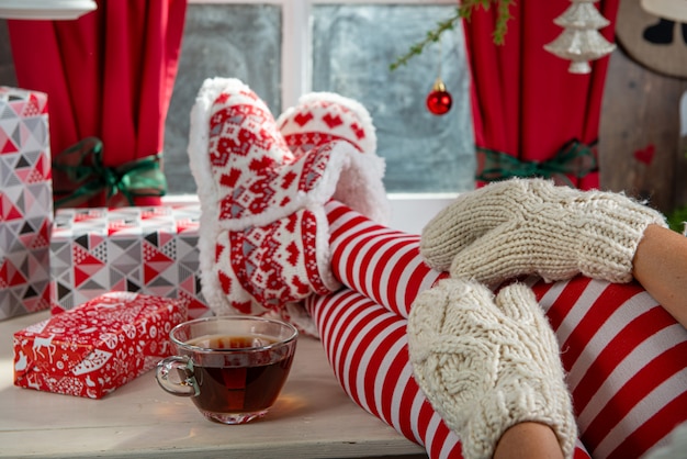 Jambes de femme avec des chaussettes sur la table et le fond de la fenêtre, concept de Noël