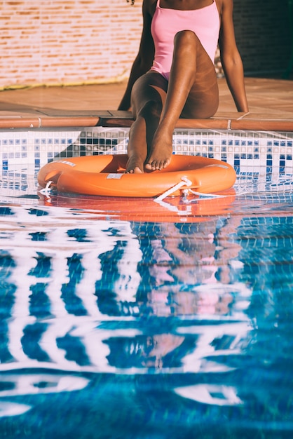 Jambes de femme dans une piscine avec bouée de sauvetage