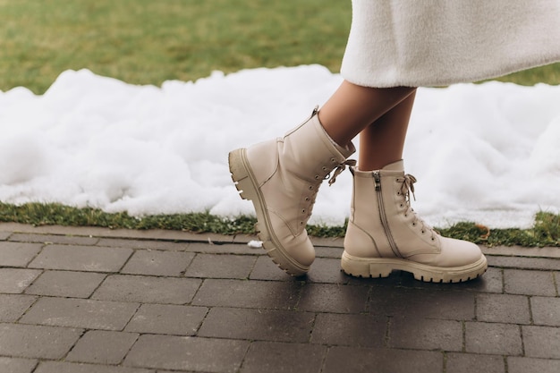 Photo des jambes de femme en hauteur, des bottes hautes, des chaussures, marchant dans la neige, l'hiver, le froid dehors.
