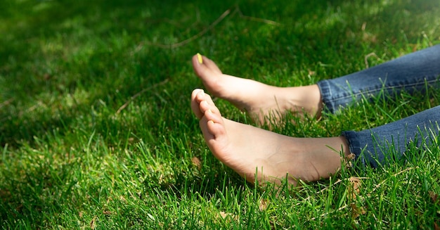 Les jambes de la femme se détendent sur fond d'herbe verte