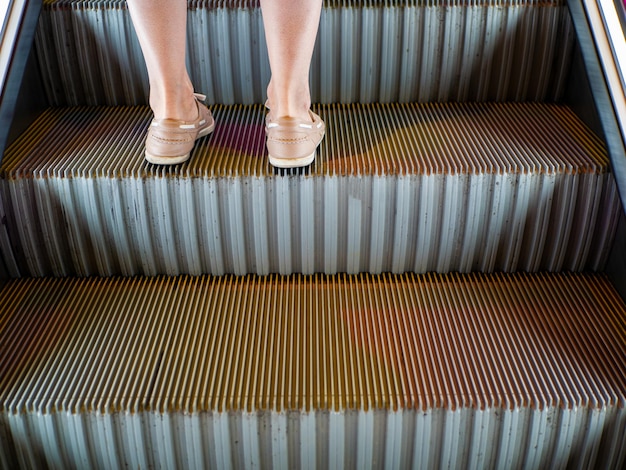 Les jambes des femmes debout sur l'escalier des escalators