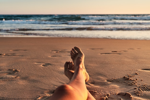 Jambes de femmes sur la plage au coucher du soleil