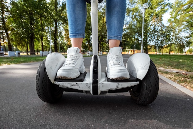 Jambes d'une fille en baskets blanches sur un hoverboard blanc dans un parc