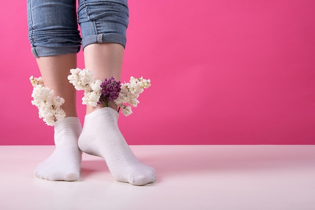 Jambes de fille dans des chaussettes dans lesquelles des fleurs lilas sont insérées concept de veines et de jambes de santé féminine