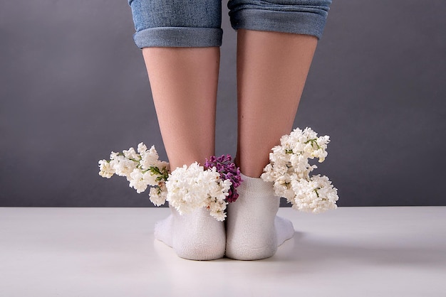 Jambes de fille dans des chaussettes dans lesquelles des fleurs lilas sont insérées concept de veines et de jambes de santé féminine