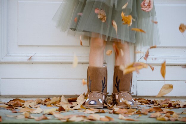 jambes de fille enfant debout sur des feuilles dans des bottes chaudes uggs