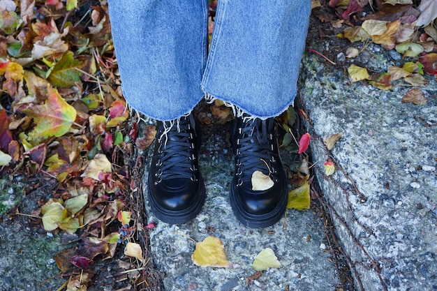 Jambes de la fille sur les escaliers dans le parc d'automne en bottes noires vue de dessus Concept d'automne