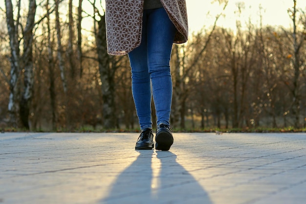 Photo jambes d'une fille en jeans marchant à l'extérieur dans le parc