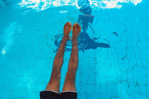 Les jambes de l'homme afro-américain adulte sous l'eau dans la piscine