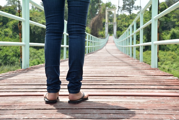 jambes d'un homme femme debout sur un pont suspendu