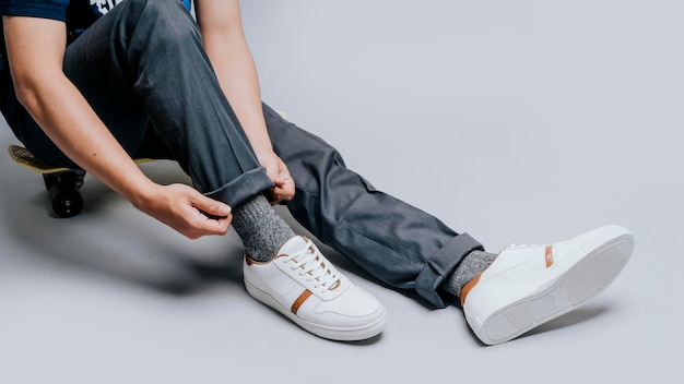 Photo jambes d'homme sur un mini longboard avec des baskets blanches